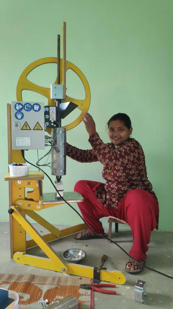 Image shows a woman operating a plasticpreneur machine while being seated